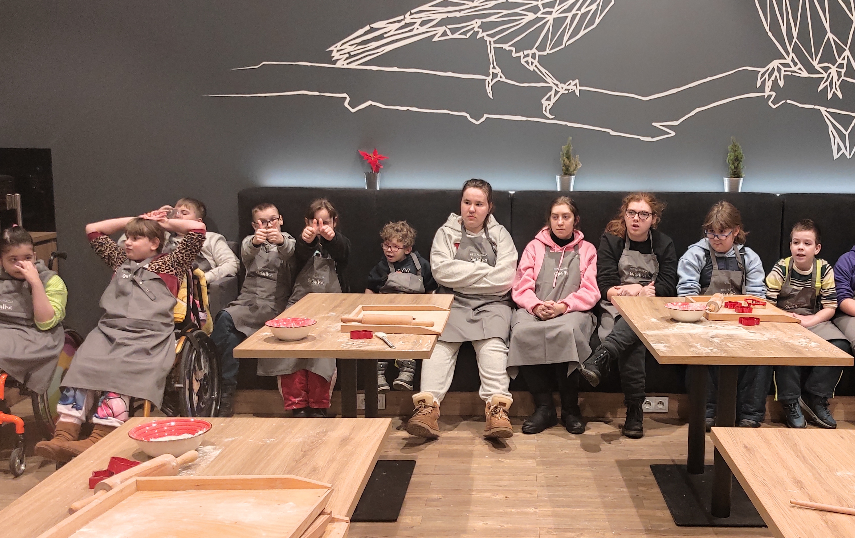 Uczestnicy półkolonii siedzą w na kanapie w restauracji. Przed nimi stoły przygotowane do warsztatów