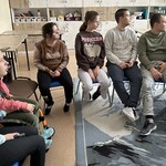 Uczniowie siedzą na krzesłach w sali.