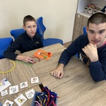Uczniowie przy stole, na którym rozłożone są artykuły papiernicze.