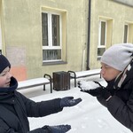 Nauczycielka dmucha na śnieg trzymany w ręce w stronę ucznia