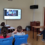 Uczniowskie siedzą w ławkach i patrzą na wyświetlany slajd na ekranie