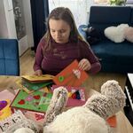 Dziewczynka siedzi przy stole, ogląda kartki z życzeniami urodzinowymi