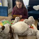 Dziewczynka siedzi przy stole, ogląda kartki z życzeniami urodzinowymi