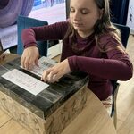 Dziewczynka siedzi przy stole, ogląda kartki z życzeniami urodzinowymi