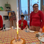 Tort ze świeczką 14 i zapalona racą. Z tyłu stoi uczennica obok siedzi solenizant