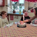 Nauczycielka zapala świeczki na torcie.