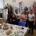 Społeczność klasowa stoi za stołem urodzinowym Marysi