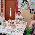 Społeczność klasowa zgromadzona przy urodzinowym stole Marysi