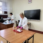Nauczyciel przygotowuje eksperyment przy stanowisku.