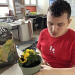 Uczeń trzyma doniczkę z posadzonym bratkiem