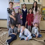 Nauczycieli, pomoc nauczyciela i uczniowie pozują do wspólnego zdjęcia