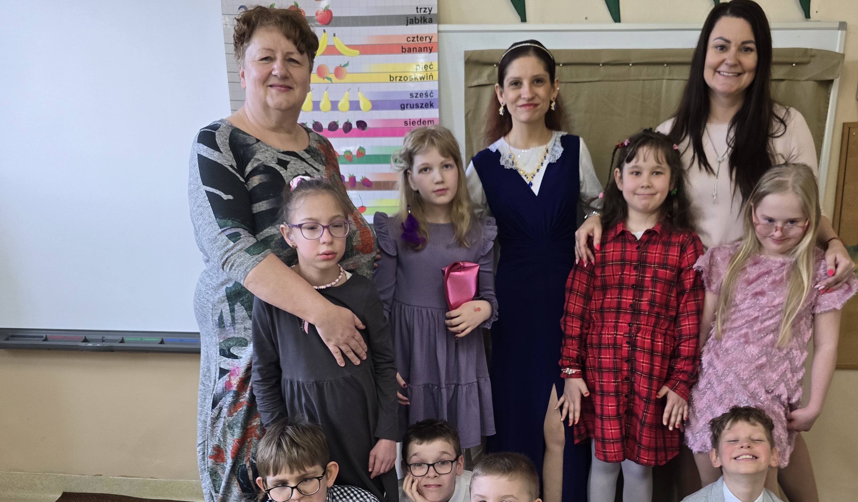 Nauczycieli, pomoc nauczyciela i uczniowie pozują do wspólnego zdjęcia