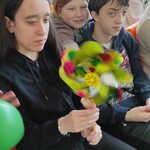 Uczennica trzyma w dłoniach kręcący się wiatrak