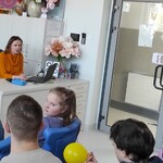 Uczniowie patrzą na nauczycielkę siedzącą za biurkiem