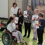 Uczennica na wózku czyta napisy z kartek trzymanych przez uczniów