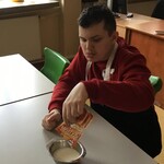 Uczeń wsypuje proszek budyniowy do miseczki