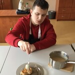 Uczeń nakłada łyżką budyń do foremki z ciasta francuskiego