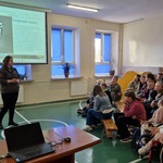 Pani leśnik omawia slajd wyświetlany na ekranie.Uczniowie siedzą na ławeczkach.