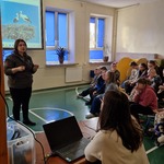 Pani leśnik omawia slajd wyświetlany na ekranie.Uczniowie siedzą na ławeczkach.