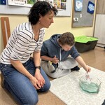 Uczeń wkłada bibułę z rysunkiem do miski z wodą