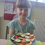 Uczennica trzyma talerz z kanapkami