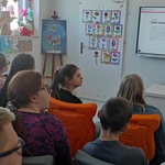 Uczniowie uczestniczący w lekcji patrzą na nauczycielkę omawiającą slajd wyświetlany na tablicy