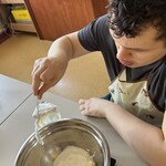 Uczeń wkłada łyżką do miski jogurt