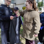 Uczennica wrzuca śmieć do worka trzymanego przez ucznia