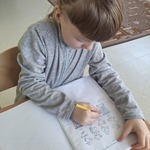 Uczennica siedzi przy stoliku i uzupełnia kartę pracy