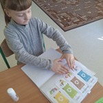 Uczennica siedzi przy stoliku i uzupełnia kartę pracy