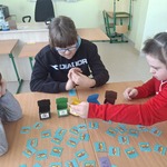 Uczennice siedzą przy stoliku i segregują śmieci - grają w grę stolikową