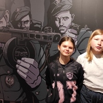 Uczennice na tle plakatu prezentowanego na ścianie w muzeum