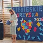 Pani stoi na tle dekoracji z napisem - Niebieskie igrzyska 2026