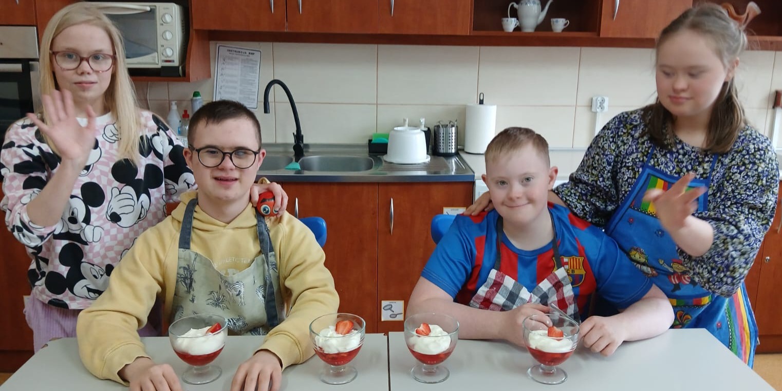 Uczniowie pozują do zdjęcia z przygotowanymi deserami.