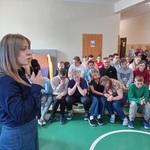 Pani prowadząca spotkanie mówi do uczniów siedzących na ławkach