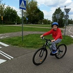 Uczeń jedzie rowerem po ścieżce w miasteczku rowerowym,