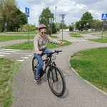 Uczennica jedzie rowerem po ścieżce w miasteczku rowerowym,
