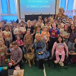 Wspólne zdjęcie uczniów i ich  pluszaków i osoby niewidomej z psem przewodnikiem.