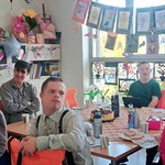 Solenizant i koledzy z klasy siedzą przy urodzinowym stole