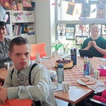 Solenizant i koledzy z klasy siedzą przy urodzinowym stole