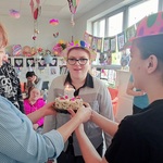 Ania gasi świeczki na torcie trzymanym przez nauczycielkę i koleżankę z klasy