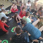 Uczniowie siedzą na podłodze, wykonują pracę plastyczną.