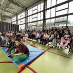 Społeczność szkolna zgromadzona na sali gimnastycznej uczestnicząca a imprezie