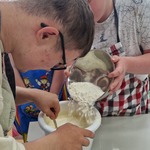Uczeń wsypuje mąkę do miski a drugi miesza łyżką