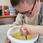 Uczeń miesza ciasto łyżką w misce