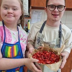 Dwoje uczniów trzyma przed sobą surowe ciasto w formie.