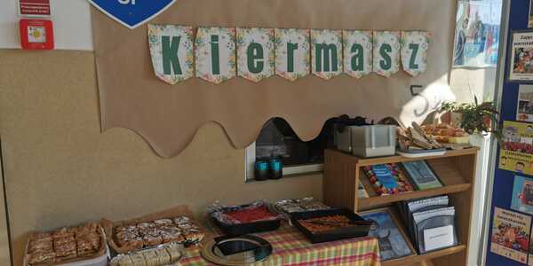 Stół z ciastami. Nad nim napis kiermasz