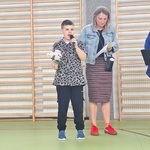 Uczeń recytuje tekst, obok stoi nauczycielka