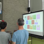 Nauczyciel i uczeń stoją przed ekranem na którym wyświetlany jest slajd