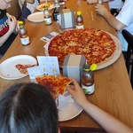 Uczestnicy półkolonii siedzą przy stołach w pizzerni